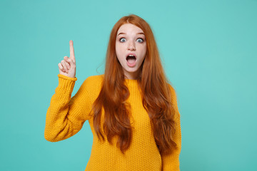 Excited young redhead woman girl in yellow sweater posing isolated on blue turquoise background...