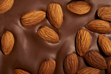 A bar of milk chocolate with whole almonds close-up