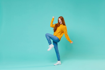 Overjoyed young redhead woman girl in yellow sweater posing isolated on blue turquoise background...