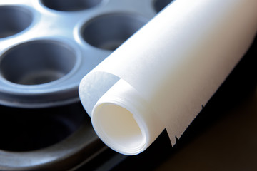 Roll of baking paper lying on metal muffin molds