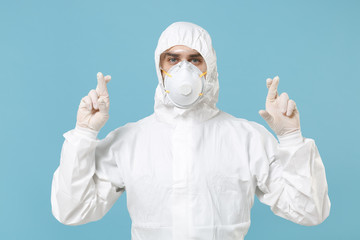 Man in white protective suit respirator mask isolated on blue background studio. Epidemic pandemic new rapidly spreading coronavirus 2019-ncov originating in Wuhan China, medicine flu virus concept.