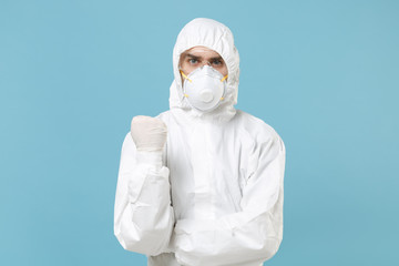 Fototapeta na wymiar Man in white protective suit respirator mask isolated on blue background studio. Epidemic pandemic new rapidly spreading coronavirus 2019-ncov originating in Wuhan China, medicine flu virus concept.