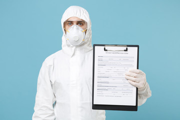 Man in white protective suit respirator mask hold clipboard with paper document isolated on blue background studio. Epidemic pandemic rapidly spreading coronavirus 2019-ncov medicine flu virus concept