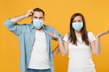 Two people in sterile face masks white t-shirts isolated on yellow background studio. Epidemic...