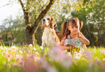 Obraz premium Happy little girl playing with dog in garden.