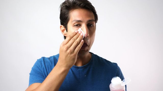 Handsome young Caucasian man put moisturizer lotion to cotton pad for cleaning beauty face, anti aging. Attractive guy use cleansing daily before apply moisturizer on his face. Skin care concept