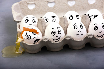 An empty shell, broken egg with different faces. Eggs in box