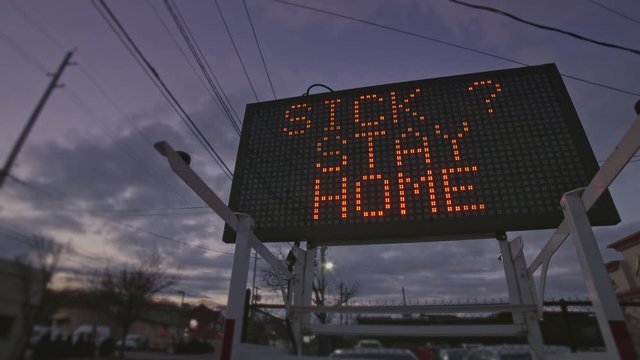 Stay at Home road sign urging people to shelter inside during the 2020 Corona Virus outbreak. Sign showing "Avoid Large Crowds" and "Sick? Stay Home" message 