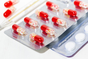 medicines in tablets and capsules, a thermometer, closeup