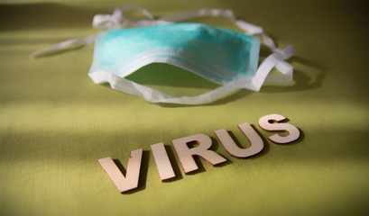 Face mask on a green background with the word virus. Coronavirus