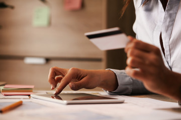 Close-up of businesswoman using touchpad and credit card while buying on the Internet.