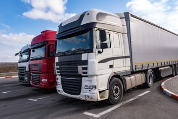 Trucks in a row with containers in the parking lot. Logistic and Transport concept