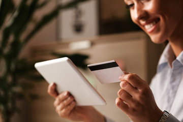 Close-up of happy woman buying online with credit card and touchpad.