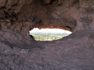 View through the Hole-in-the-Rock formation at Papago Park located in Phoenix and Tempe, Arizona with mountains and blue sky in the background 