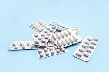 Pills in blister packs on blue background. Medicine concept.
