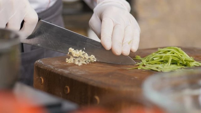 Cutting garlic with a sharp knife. The hands of the chef with a knife. Restaurant kitchen