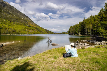 Beautiful Pyrenees mountain landscape, nice lake with tourist woman looking a map from Spain, Catalonia.