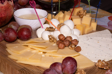 wooden tray with cheese fruit and nuts, pomegranate and grape