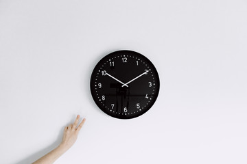  clock on white wall with one hand making peace gesture next to clock