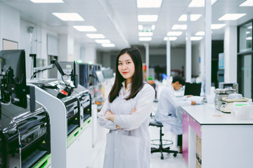 young smiling scientist in white lab coat standing with automation blood analyzer at medical...