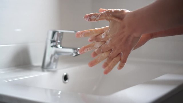 Persona lavando las manos para desinfectar y prevenir la infecci&oacute;n de corona virus con agua y jab&oacute;n en el ba&ntilde;o 4k