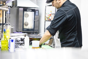 Chef in the kitchen at the restaurant prepares dishes