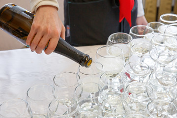 The waiter pours champagne into the glasses