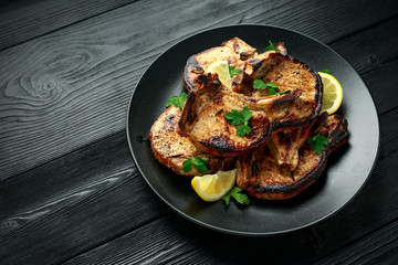 Homemade Grilled Pork loin chops in lemon sauce with herbs on rustic wooden table