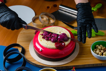 Pastry chef cuts a trendy mousse cake. Preparation of the modern dessert.
