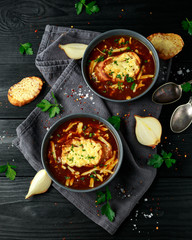 French onion soup with cheese toast on rustic background