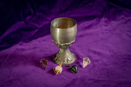 Close up of tin goblet and four dowsing pendulums