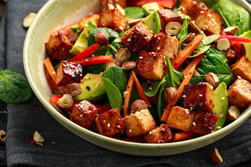Healthy Vegan Fried Tofu salad with carrot, red bell pepper, spinach and nuts