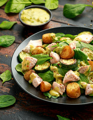 Salmon, new potato, courgette and spinach salad on wooden table