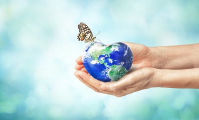 Together we can safe the world and offer the better world for our children and Earth day concept, Butterfly and love heart shaped earth on hands, Elements of this image furnished by NASA