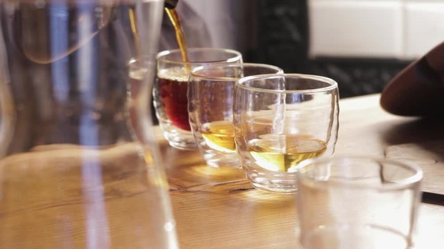 Pouring tea or coffee into cups. Barista making irish coffee close up.