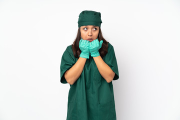 Surgeon woman in green uniform isolated on white background nervous and scared putting hands to mouth