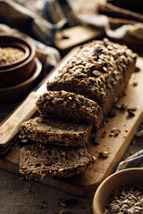 Gluten-free homemade buckwheat bread with the addition of various seeds on a wooden board close up