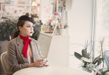 Portrait of a young beautiful woman in vintage style in a cafe.