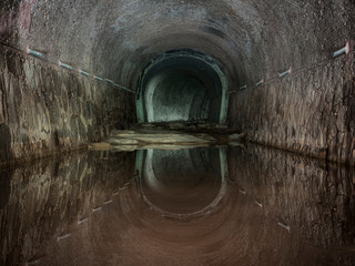 Túnel abandonado de desagüe de agua con reflejo del techo.
