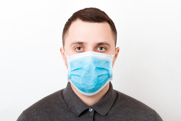 Portrait of young man wearing medical mask at white background. Coronavirus concept. Respiratory protection