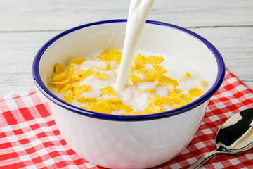 Breakfast with cornflakes. Pour milk into a bowl with corn flakes. The yogurt splashes out into cornflakes. Healthy breakfast. Food and drink industry