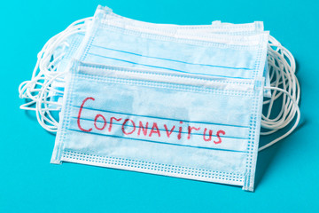 Top view of blue background with coronavirus word on protective medical masks. Respiratory...