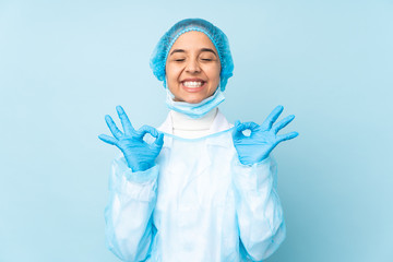 Young surgeon Indian woman in blue uniform in zen pose