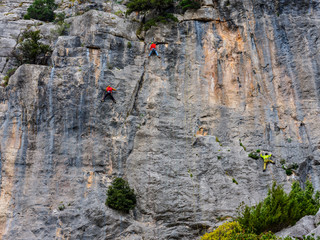 Rock climbers climbing on the cliffs of Baunei, est coast of Sardinia, Italy