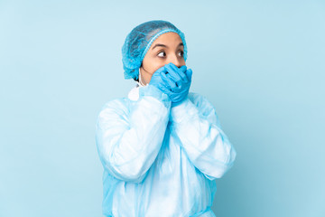 Young surgeon Indian woman in blue uniform covering mouth and looking to the side