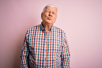 Senior handsome hoary man wearing casual colorful shirt over isolated pink background looking at...