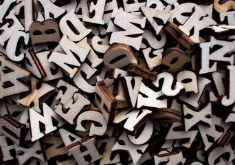 Pile of wooden block letters on the wooden background as a typography background composition concept.