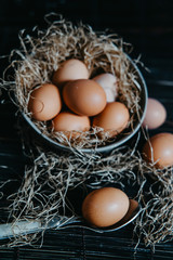 eggs in a plate with straw on a black surface