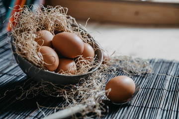 eggs in a plate with straw on a black surface