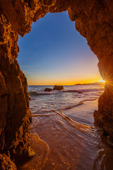 Blick vom Strand durch eine Felsformation auf den Atlantik, Sonnenuntergang an der Algarve, Portugal